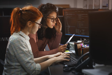 Two female programmers working on new project.They working late at night at the office.