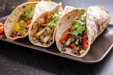 Plate with tasty tacos on table