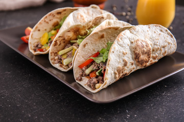 Plate with tasty tacos on table