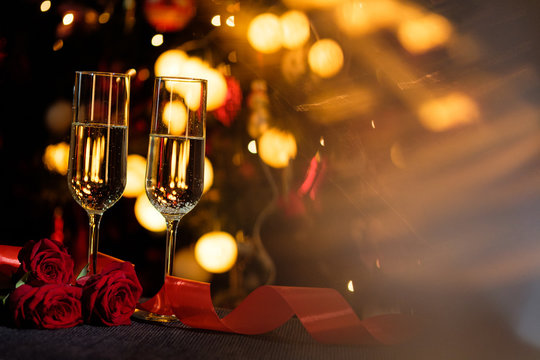Glasses of champagne on the background of lights with roses and red ribbon