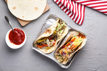 Tasty tacos with sauce on grey table