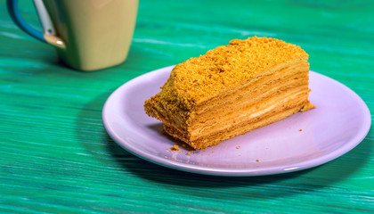 A piece of cake and a cup of coffee on a green wooden background.