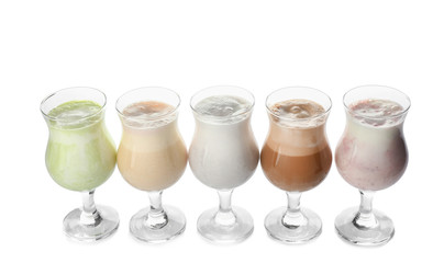 Glasses of tasty milkshakes on white background