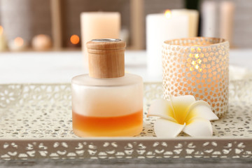 Bottle of essential oil with aroma candle on light tray