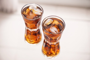 Glasses of tasty cold cola drink on light table