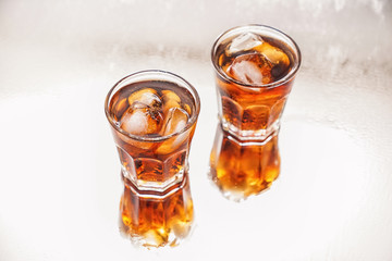 Glasses of tasty cold cola drink on light table