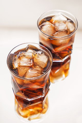 Glasses of tasty cold cola drink on light table
