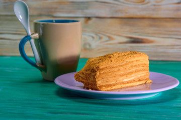 A piece of cake and a cup of coffee on a green wooden background.