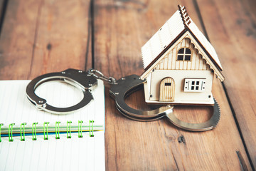 house model and handcuffs on notepad