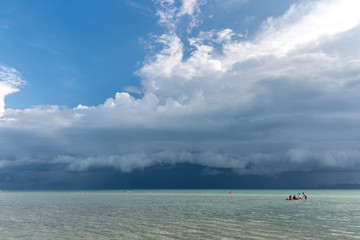 Tourist kayaking in the emerald Thailand sea at the cloudy blue sky background