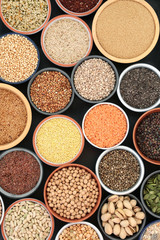 Dried health food for body builders with legumes, grains, seeds and nuts in bowls forming a background. top view. Foods high in omega 3, antioxidants, protein, anthocyanins, dietary fibre & vitamins.
