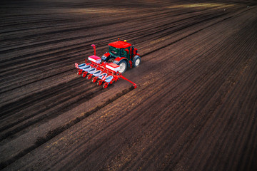 Obraz premium Farmer with tractor seeding crops at field, aerial drone view