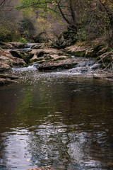 Naklejka na ściany i meble A running river through the rocks of the mountain in autumn.
