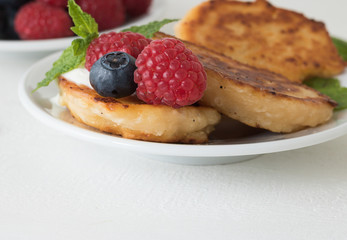 Close-up: Fresh fruit and pancakes are on plate on white wooden table background with copy space for your simple text. Concept: healthy food and tasty breakfast.