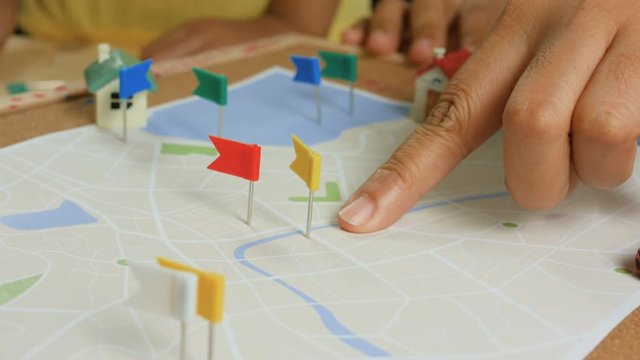 Close up shot hand of kids and mother pinning color pin at the map metaphor planning for transport and travel