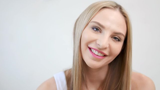 Close-up portrait of charming European woman wearing natural makeup looking at camera and smiling