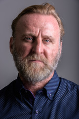 Face of mature bearded man in gray background