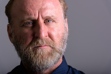Close up portrait of mature bearded man looking at camera