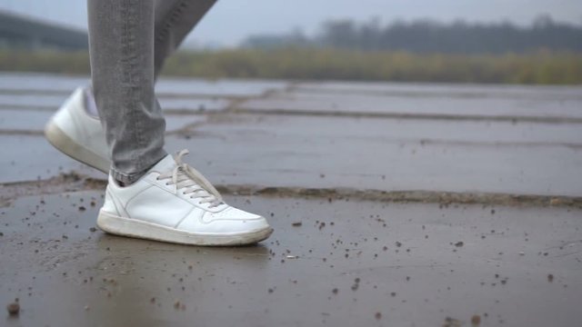 Shot of men feets in sneakers walking on tile road. Urban Environment