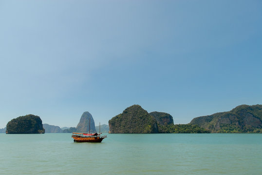 Wooden boat near limestone islands in the sea in Thailand