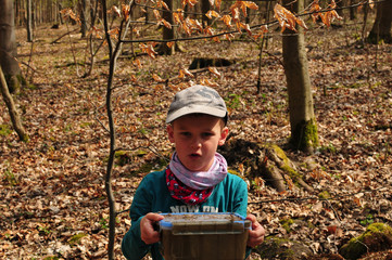 geocaching boy finds a well camouflaged cache in the forest