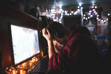 Portrait of the frustrated gamer with his downed hands losing in the game. Frustrated teenager sits at a computer desk and is sad. Gamer failed because of that disappointment. - obrazy, fototapety, plakaty