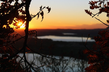 Tree branches without leaves and lakes in the background at sunset