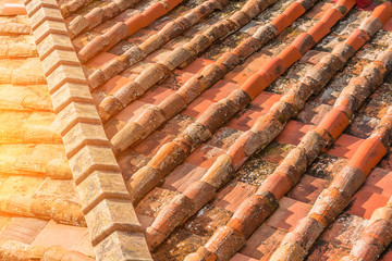 Ceramic orange clay tiles on the roof of a building, corner sunlight glare.