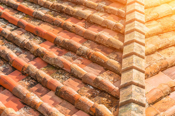 Ceramic orange clay tiles on the roof of a building, corner sunlight glare