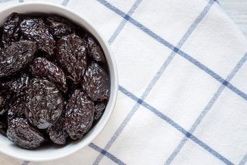 Full bowl of dry prunes, top view. Flat lay, from above, overhead. Copy space.