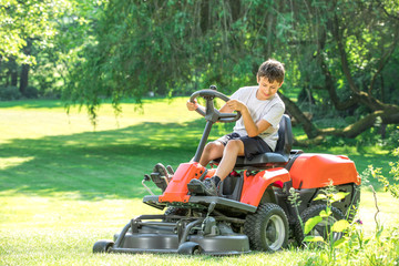 young man, father with son with a grass trimmer mows the lawn. Meadow in summer. Spring in the green garden