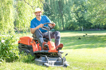 junger Mann, Vater mit Sohn mäht mit einem Rasentrimmer den Rasen Wiese im Sommer Frühling im grünen Garten