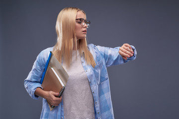 Worried young lady with documents checking time