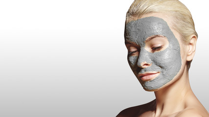 Beautiful Woman Applying White Facial Mask. Beauty Treatments. Spa Girl Apply Clay Facial mask on grey background