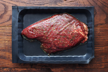 Raw marinated steak with different spices and herbs top view