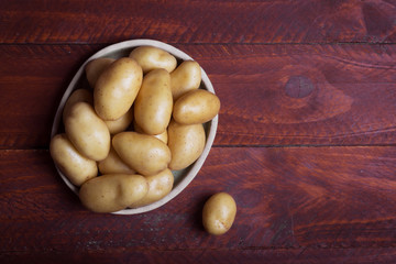 Pile of raw potatoes in the bowl on dark background