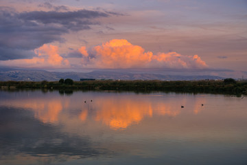 Sunset colored clouds over Santa Cruz mountains reflected in the ponds of south San Francisco bay,...