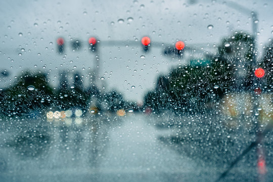 Waiting at a traffic junction for the green light during a rainy day; raindrops on the windshield