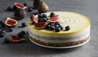 Vegan raw cheesecake with blueberry and figs, cashew cream, coconut butter and coconut milk, and base made of almonds, dates and dried apricots, oat flakes, lyophilisated berry