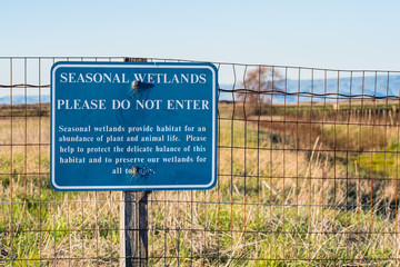 "Seasonal Wetlands, please do not enter" sign posted on a metal fence in Sunnyvale Baylands park, south San Francisco bay area, California