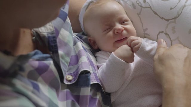 Grandfather babysitting granddaughter. Loving grandpa looking at lovely baby and touching her nose and hands