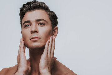 Thoughtful man touching cheeks after shaving them