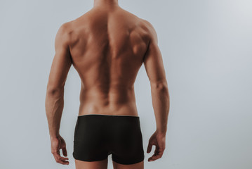 Back of muscular man in black underwear standing alone - obrazy, fototapety, plakaty