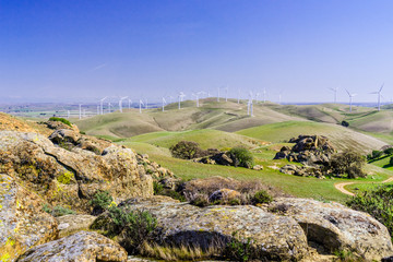 Fototapeta na wymiar Rock formations on the hills of Costa Contra county; wind turbines in the background, east San Francisco bay area, California