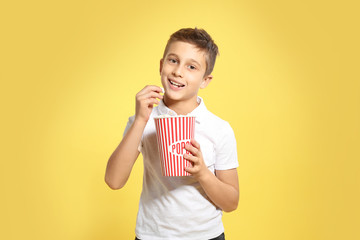 Boy with popcorn during cinema show on color background