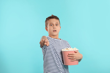 Fototapeta premium Emotional boy with popcorn during cinema show on color background