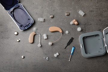 Flat lay composition with hearing aids and accessories on grey background
