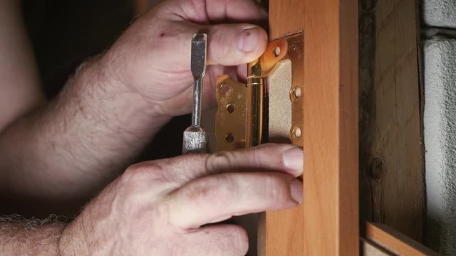 Close-up carpenter process of wood door hinge installation. Door hinge installation.
