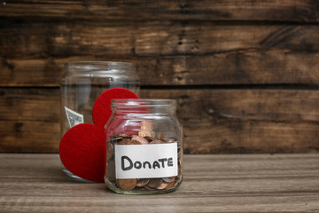 Donation jars with money and red heart on table. Space for text