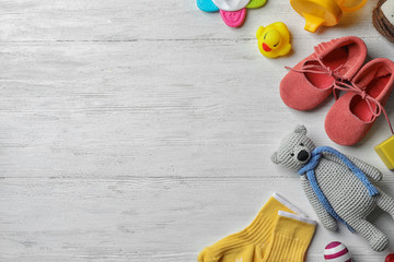 Flat lay composition with baby accessories and toys on light wooden background. Space for text